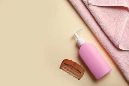 Bottle with shampoo, towel and comb on color background, flat lay. Space for textの写真素材