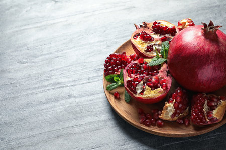 Plate with ripe pomegranates on gray background. Space for textの写真素材