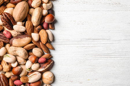 Organic mixed nuts on white wooden background, top view with space for textの写真素材