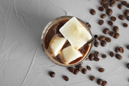 Coffee drink with milk ice cubes and beans on gray background, top viewの写真素材