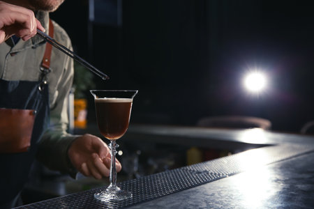 Barman adding coffee bean to martini espresso cocktail at counter, closeup. Space for textの写真素材