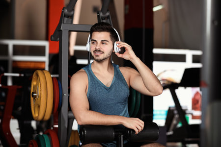Young man listening to music with headphones at the gymの写真素材