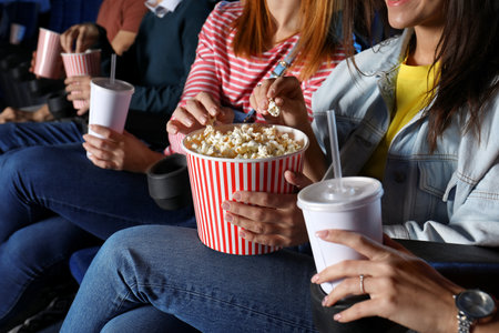 Young people eating popcorn during showtime in cinema theaterの写真素材