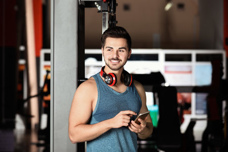 Young man with headphones and mobile device at gymの写真素材