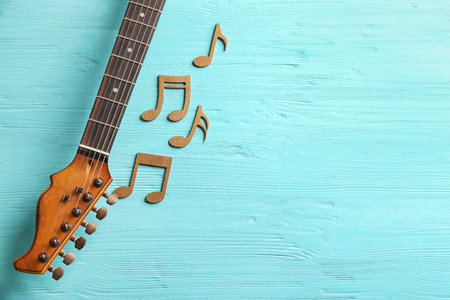 Guitar neck and music notes on wooden background, flat lay. Space for textの写真素材