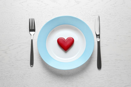 Plate with red wooden heart and cutlery on white background, flat lay. healthy diet conceptの写真素材