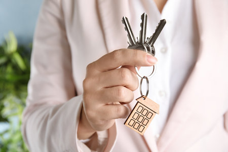 Woman holding bunch of house keys with trinket on blurred background, closeupの写真素材