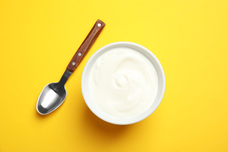 Bowl with creamy yogurt and spoon on color background, top viewの写真素材