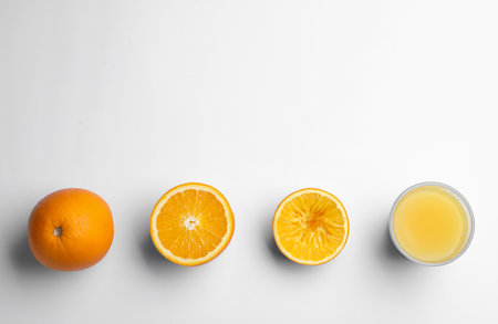 Fresh and squeezed oranges with juice in glass on white background, top viewの写真素材