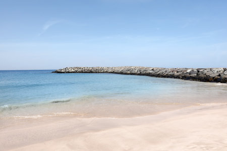 Picturesque view of beautiful beach with stone breakwater on sunny dayの写真素材