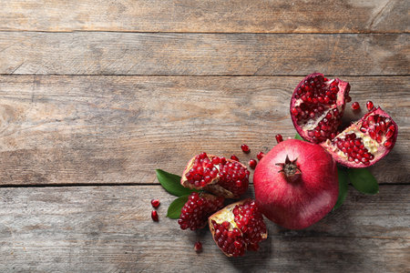 Composition with ripe pomegranates and space for text on wooden background, top viewの写真素材