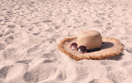 Straw hat with sunglasses on sandy beach. Space for textの写真素材