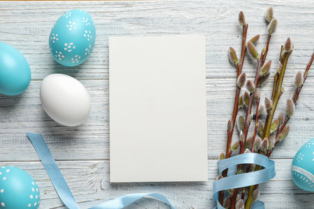 Flat lay composition with painted Easter eggs and blank card on wooden background, space for textの写真素材