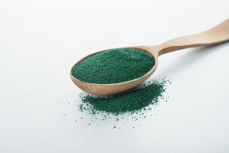 Spoon with spirulina algae powder on white backgroundの写真素材