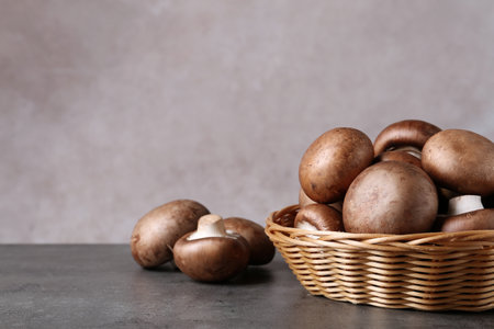 Wicker bowl and fresh champignon mushrooms on table against color background. Space for textの写真素材