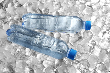 Bottles of water on pile of ice cubesの写真素材