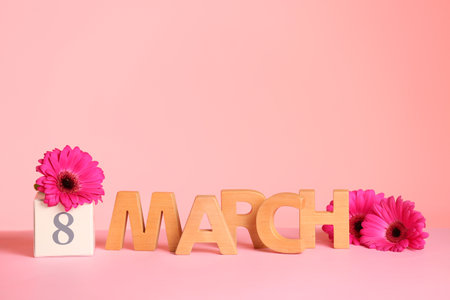 Women's Day composition with flowers and wooden letters on table against color background, space for...
