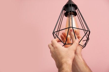 Man changing light bulb in lamp on color background. Space for textの写真素材