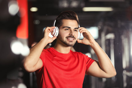 Young man listening to music with headphones at the gymの写真素材