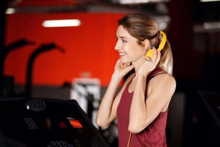 Beautiful young woman with headphones at the gymの写真素材
