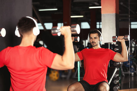 Young man with headphones listening to music and working out at the gymの写真素材