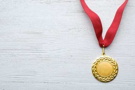 Gold medal with space for design on white wooden background, top view. Victory conceptの写真素材