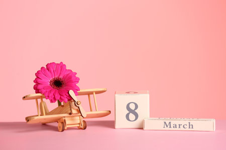 Composition with wooden plane and flower on table against color background, space for text. International Women's Dayの写真素材