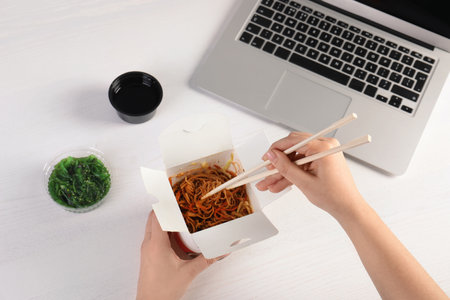 Woman eating tasty Chinese noodles at workplace, closeup. food deliveryの写真素材