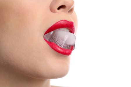 Young woman holding ice cube in mouth on white background, closeupの写真素材