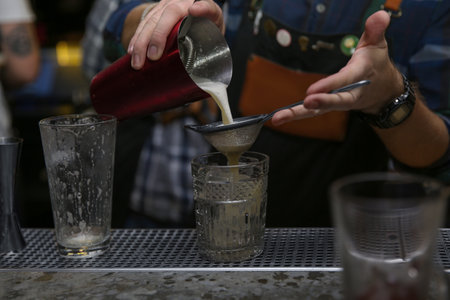 Bartender pouring tasty cocktail at counter in nightclub, closeupの写真素材