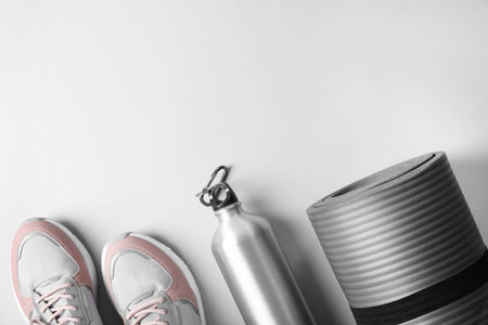 Yoga mat, sneakers and bottle of water on light background, top view with space for text. fitness equipmentの写真素材