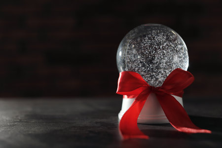 Christmas snow globe with red bow on dark background. Space for textの写真素材
