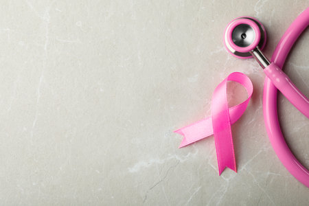 Pink ribbon and stethoscope on gray background, top view with space for text. breast cancer conceptの写真素材