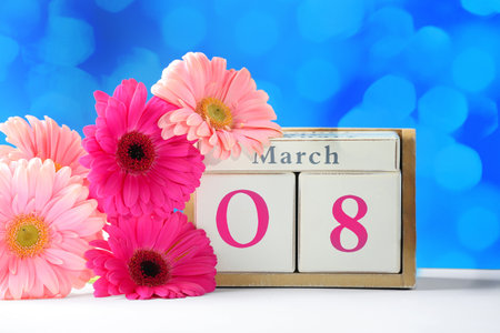 Calendar and flowers on table against color background. International Women's Dayの写真素材
