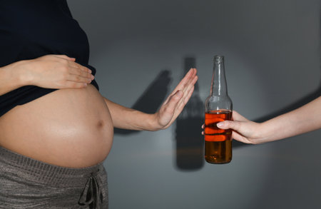 Pregnant woman declining whiskey on dark background. Alcohol harmの写真素材