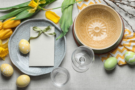 Festive Easter table setting with blank card on color background, top view. Space for textの写真素材