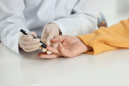 Doctor taking patient's blood sample with lancet pen in hospital, closeup. diabetes controlの写真素材