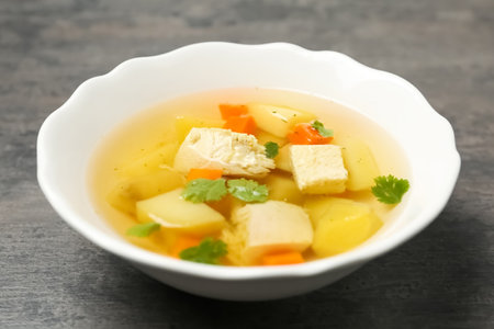 Dish with fresh homemade chicken soup on gray tableの写真素材
