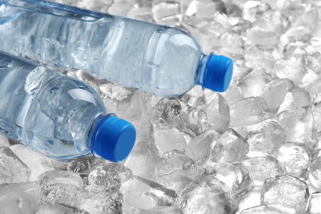 Bottles of water on pile of ice cubesの写真素材