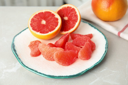 Plate with yummy grapefruits on gray tableの写真素材