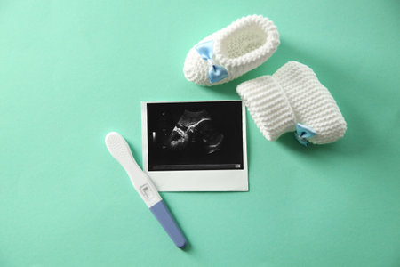Ultrasound picture, baby shoes and pregnancy test on color background, top viewの写真素材