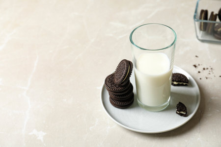 Plate with chocolate sandwich cookies and milk on gray table. Space for textの写真素材