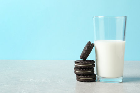 Chocolate sandwich cookies and glass of milk on table against color background. Space for textの写真素材