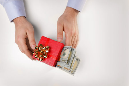 Man holding gift box with dollar banknotes on white background, top viewの写真素材