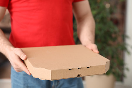 Courier with pizza box on blurred background, closeup. Space for textの写真素材