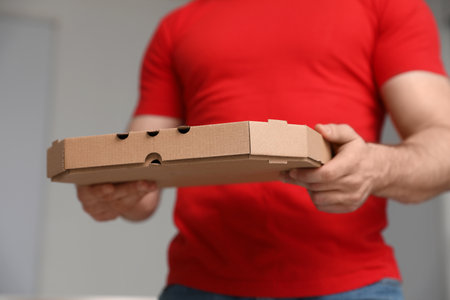 Courier with pizza box on blurred background, closeupの写真素材
