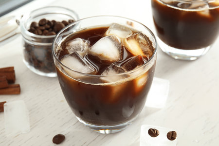 Glass of coffee drink with ice cubes on tableの写真素材