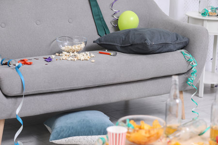 Living room interior with messy sofa. After party chaos