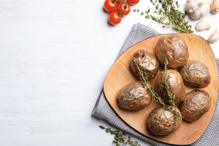 Plate with tasty baked jacket potatoes on wooden background, flat lay. Space for textの写真素材