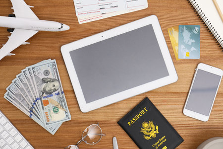 Flat lay composition with airplane model and tablet on wooden table in travel agencyの写真素材